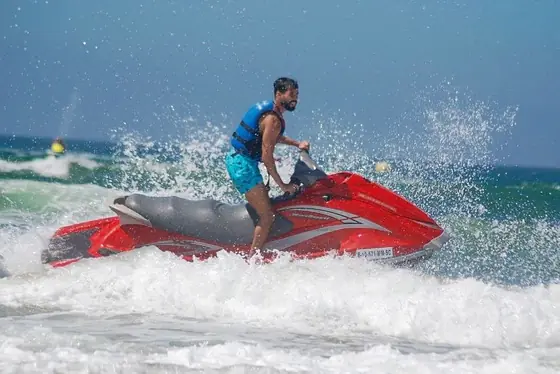 A rider on a red jet ski throwing up a wall of spray