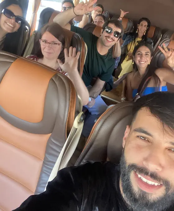 A minibus full of smiling, waving passengers on the way to a day trip